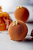 A chocolate truffle decorated with gold leaf