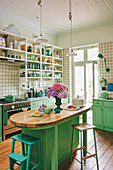 Bright country-style kitchen with green cabinets and wooden floor