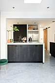 Modern kitchen with dark cabinet front, light-coloured walls and skylight