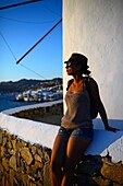 Junge Frau genießt den Sonnenuntergang von den traditionellen Windmühlen (Kato Milli) in Mykonos-Stadt, Griechenland