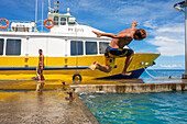 Teens jumping into the water next to Bora Bora Vaitape dock, Society Islands, French Polynesia, South Pacific.