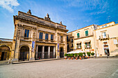 Noto Theatre (Teatro Comunale Vittorio Emanuele) and Caffe del Teatro in Piazza XVI Maggio, Val di Noto, UNESCO World Heritage Site, Sicily, Italy, Europe. This is a photo of Noto Theatre (Teatro Comunale Vittorio Emanuele) and Caffe del Teatro in Noto, in an area known as Val di Noto, which is listed as a UNESCO World Heritage Site in Sicily, Italy, Europe. Noto Theatre (Teatro Comunale Vittorio Emanuele) in Noto is a building typical of the Sicilian Baroque style of architecture. Noto is one of eight towns recognised for its stunning Baroque architecture that make up the UNESCO World Heritag