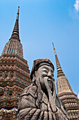 Steinwächterstatue und Tempeltürme (chedi) im Wat Pho, dem Tempel des liegenden Buddhas, dem größten buddhistischen Tempel in Bangkok, Thailand, und dem Geburtsort der Thai-Massage.