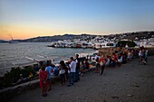 Menschen genießen die Aussicht auf Mykonos-Stadt bei Sonnenuntergang, Griechenland