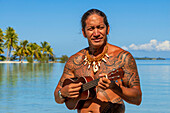 Insel Taha'a, Französisch-Polynesien. Ein einheimischer Junge spielt die Ukulele, um ein Mädchen auf dem Motu Mahana zu umwerben, Taha'a, Gesellschaftsinseln, Französisch-Polynesien, Südpazifik.