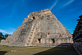 Die Westfassade der Pyramide des Magiers, die auch als Pyramide des Zwerges bekannt ist, blickt auf das Viereck der Vögel. Mit einer Höhe von 35 Metern ist sie das höchste Bauwerk in den prähispanischen Maya-Ruinen von Uxmal, Mexiko. Der Tempel am oberen Ende der Treppe ist im Chenes-Stil gebaut, während der obere Tempel im Puuc-Stil gehalten ist.