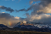 Wolken verdecken das Fitz-Roy-Massiv im Los-Glaciares-Nationalpark bei El Chalten, Argentinien. Ein UNESCO-Weltnaturerbe in der Region Patagonien in Südamerika. Zu sehen sind der Loma de las Pizarras und der Techado Negro, mit einem teilweisen Regenbogen über dem Torre-Tal.