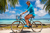 Touristenmädchen mit einem Fahrrad in Fakarava, Tuamotus-Archipel, Französisch-Polynesien, Tuamotu-Inseln, Südpazifik.