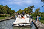 Der Canal du Midi, in der Nähe von Carcassonne, französisches Departement Aude, Region Occitanie, Languedoc-Rousillon Frankreich. Boote, die auf dem von Bäumen gesäumten Kanal vertäut sind. Die Herminis-Schleuse oder Herminis ecluse.