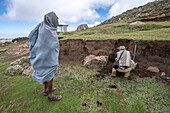 Einheimische äthiopische Bauern beobachten, wie ein Feldforscher den Boden eines Hügels untersucht, Debre Berhan, Äthiopien.