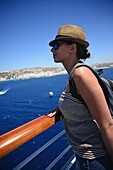 Junge Frau mit Blick auf Mykonos vom Kreuzfahrtdeck aus