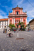 Tourist radelt an der Franziskanerkirche Mariä Verkündigung am Presernov Trg (Preseren-Platz) vorbei, Ljubljana, Slowenien, Europa