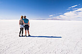 Young tourist couple on vacation while traveling on a gap year, experiencing the amazing, unique landscape of Uyuni Salt Flats (Salar de Uyuni), Uyuni, Bolivia