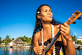 Schöne einheimische Frau spielt Ukulele am Strand von Rangiroa, Tuamotu-Inseln, Französisch-Polynesien, Südpazifik.