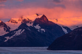 Ein farbenprächtiger Sonnenaufgang über dem Perito-Moreno-Gletscher im Los-Glaciares-Nationalpark in der Nähe von El Calafate, Argentinien. Ein UNESCO-Weltnaturerbe in der Region Patagonien in Südamerika. Der Gipfel des Cerro Dos Picos ist in den Wolken versteckt.
