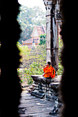 Buddhistischer Mönch beim Gebet in Angkor Wat, Kambodscha. Angkor Wat wurde im 12. Jahrhundert von Suryavarman II. erbaut. Obwohl Angkor Wat ursprünglich dem Hindu-Gott Vishnu geweiht war, ist es heute ein buddhistischer Tempel. Angkor Wat ist der berühmteste Tempel und steht daher bei den meisten Touristen ganz oben auf der Liste der "Muss-Sehenswürdigkeiten" und ist bei Sonnenaufgang und Sonnenuntergang extrem überlaufen. Es versteht sich von selbst, dass keine Reise zu den Angkor-Tempeln ohne einen Sonnenaufgang in Angkor Wat vollständig ist.