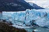 Die zerklüftete Wand des Perito-Moreno-Gletschers und der Lago Argentino im Los-Glaciares-Nationalpark bei El Calafate, Argentinien. Ein UNESCO-Weltnaturerbe in der Region Patagonien in Südamerika. Eisberge vom kalbenden Eis des Gletschers schwimmen im See.