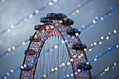 The London Eye seen through Christmas lights at night, South Bank, London, England