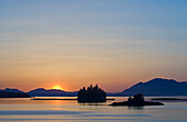 Sunset and islets on the Inside Passage, near Ward Cove, Revillagigedo Island; Ketchikan, Alaska.