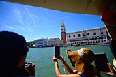 Touristen fotografieren vom Vaporetto aus, mit Blick auf den Campanile di San Marco (Glockenturm von St. Markus), Venedig, Italien