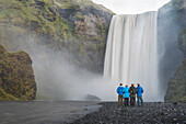 Familie im Urlaub am Skogafoss-Wasserfall, Skogar, Südregion (Sudurland), Island