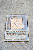 Schild "Centre of New Zealand" in Nelson, Südinsel, Neuseeland. Nelson, die Heimat des "Centre of New Zealand", ist eine sehr malerische Stadt an der Spitze der Südinsel Neuseelands. Die Lage an der Küste in Verbindung mit den umliegenden Hügeln und Bergen sorgt für eine große Vielfalt an wunderschönen Landschaften und Szenerien.