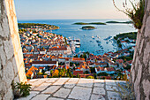 Hvar Stadt bei Sonnenuntergang, aufgenommen von der Spanischen Festung, Insel Hvar, Kroatien, Europa. Dieses Foto der Stadt Hvar und des Hafens wurde bei Sonnenuntergang von der Spanischen Festung, auch Fortica oder Hvar Spanish Fortress genannt, aufgenommen. Von der Festung, die hoch oben auf einem Hügel über der Stadt Hvar liegt, hat man den besten Blick auf die Stadt und die Insel Hvar. Der Spaziergang zur Spanischen Festung lohnt sich auf jeden Fall, besonders bei Sonnenuntergang.