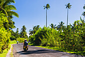 Moped driving on the circular road around Rarotonga, Cook Islands