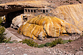 Colorful travertine deposits of the mineral spring at Puente del Inca in the Andes Mountains of Argentina, with the ruins of a former spa.