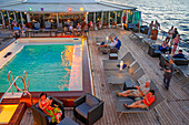 Paul Gauguin cruise ship, passengers relaxing in the upper deck in the swimming pool. Society Islands, French Polynesia, South Pacific.