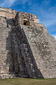 Die Westfassade der Pyramide des Magiers, die auch als Pyramide des Zwerges bekannt ist, zeigt in das Vogelviereck. Sie ist das höchste Bauwerk in den prähispanischen Maya-Ruinen von Uxmal, Mexiko, und ragt etwa 35 Meter in die Höhe. Der Tempel am oberen Ende der Treppe ist im Chenes-Stil gebaut, während der obere Tempel im Puuc-Stil gehalten ist.
