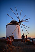 Menschen genießen den Sonnenuntergang von den traditionellen Windmühlen (Kato Milli) in Mykonos-Stadt, Griechenland