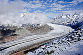 Hiker admiring Aletsch Glacier from viewpoint standing on top of rocks, UNESCO World Heritage Site, Bernese Alps, Valais canton, Switzerland, Europe