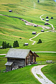 Typische alpine Holzhütten auf grünen Wiesen, Dolomiten, Puez Geisler, Bezirk Bozen, Südtirol, Italien, Europa