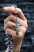 Woman praying with a silver crucifix and a rosary with beads, Concept for Christian religion, faith and prayer, Vietnam, Indochina, Southeast Asia, Asia