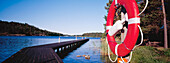 View Across Water And A Pier On Uto Island With A Life Preserver In The Foreground.