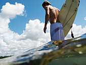 Surfer geht über ein Riff hinaus, geteilte Ebene