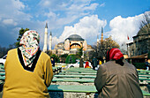 Frauen sitzen auf einer Bank bei der Moschee