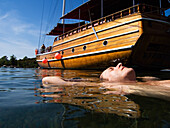 Männlicher Schwimmer schwimmt neben einem vertäuten Boot