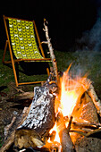 Leerer Liegestuhl und Holzfeuer am Abend