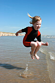 Junges Mädchen im Neoprenanzug springt ins Wasser