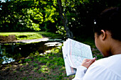 Woman Looking At Map In Forest