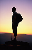 Silhouetted Man Standing On Mountain Peak