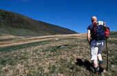 Hiker With Walking Stick On Black Mountain, Rear View