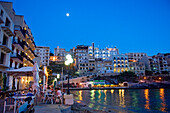 Menschen im Hafencafé an der Xlendi Bay in der Abenddämmerung