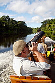 Tourist fotografiert im Boot sitzend auf dem Fluss; Peru