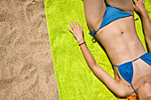 Mädchen im blauen Bikini entspannt sich am Sandstrand