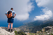 Hiker Standing On Edge Of Mountain Looking At View, Rear View