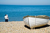 Vater und Baby hinter kleinem Fischerboot am Strand