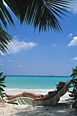 Seychellen, Praslin, Frau entspannt sich am Strand; Cote D'Or Beach